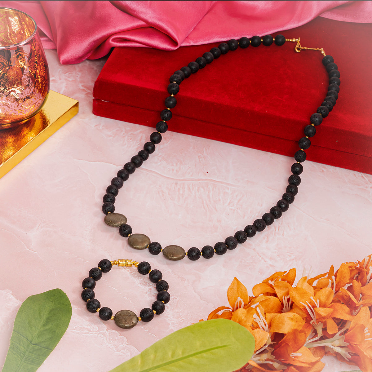 Eykaa necklace and bracelet that features lava with pyrite coins semi-precious stones displayed over a red jewellery box.