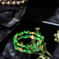 Eykaa GREEN MOTHER OF PEARL WITH GOLDEN CHARMS AND PENDANT BRACELET with black background beside silver lace.