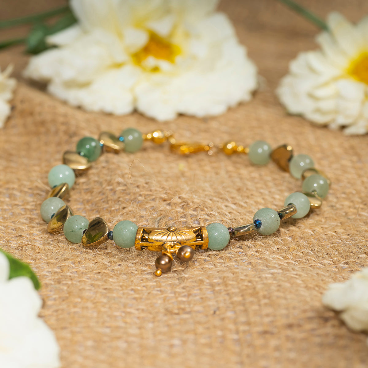 Eykaa green aventurine, golden hematite with golden charms and shell pearls semi precious stone bracelet on sack surface.