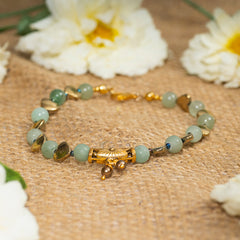 Eykaa green aventurine, golden hematite with golden charms and shell pearls semi precious stone bracelet on sack surface.