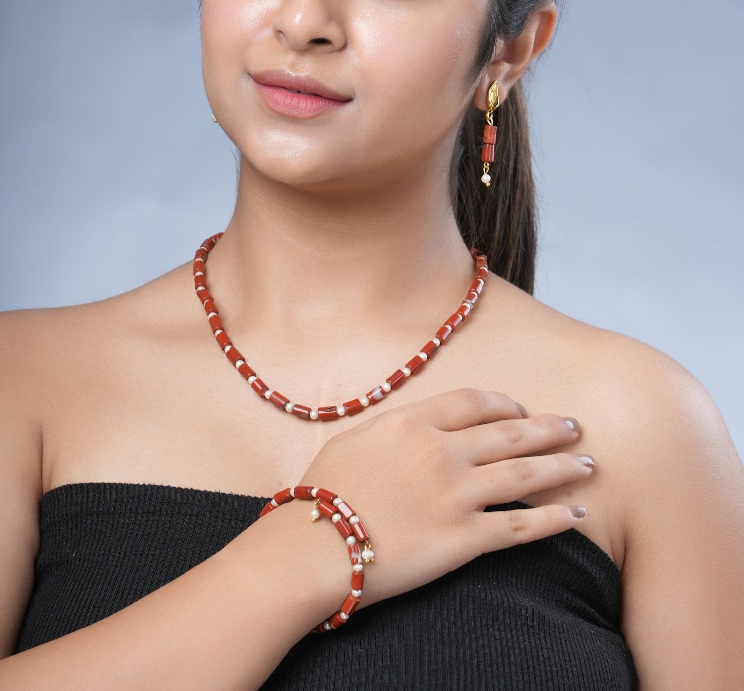 Girl model wearing Eykaa brand red jasper with shell pearls semi precious stone necklace, earrings and bracelet.