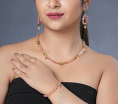 Girl model wearing Eykaa cherry quartz, golden charms and shell pearls semi precious stone earrings, necklace and bracelet.