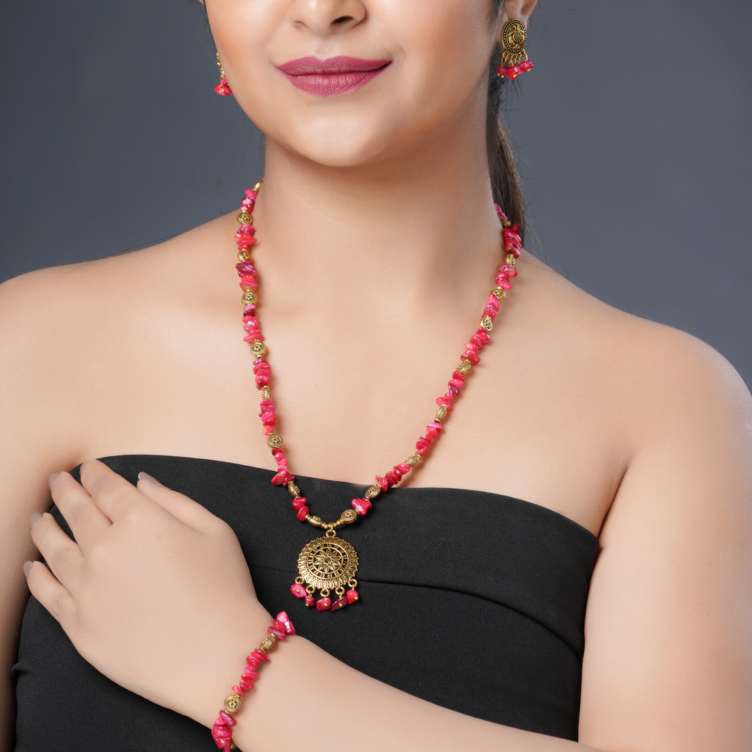 Eykaa brand jewellery features red mother of pearl semi precious stone hanging on a thin branch with green background.