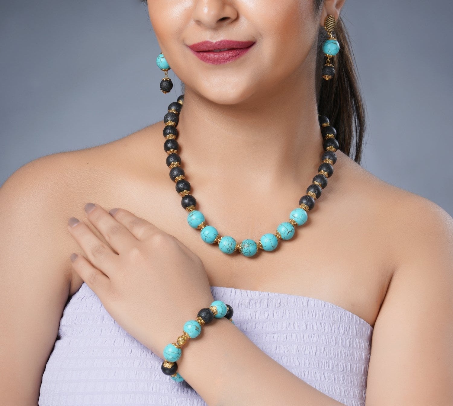 Girl model wearing Eykaa necklace, earrings and bracelet that features EYKAA FIROZA AND LAVA WITH GOLDEN CHARMS 12 MM AND 14 MM BRACELET