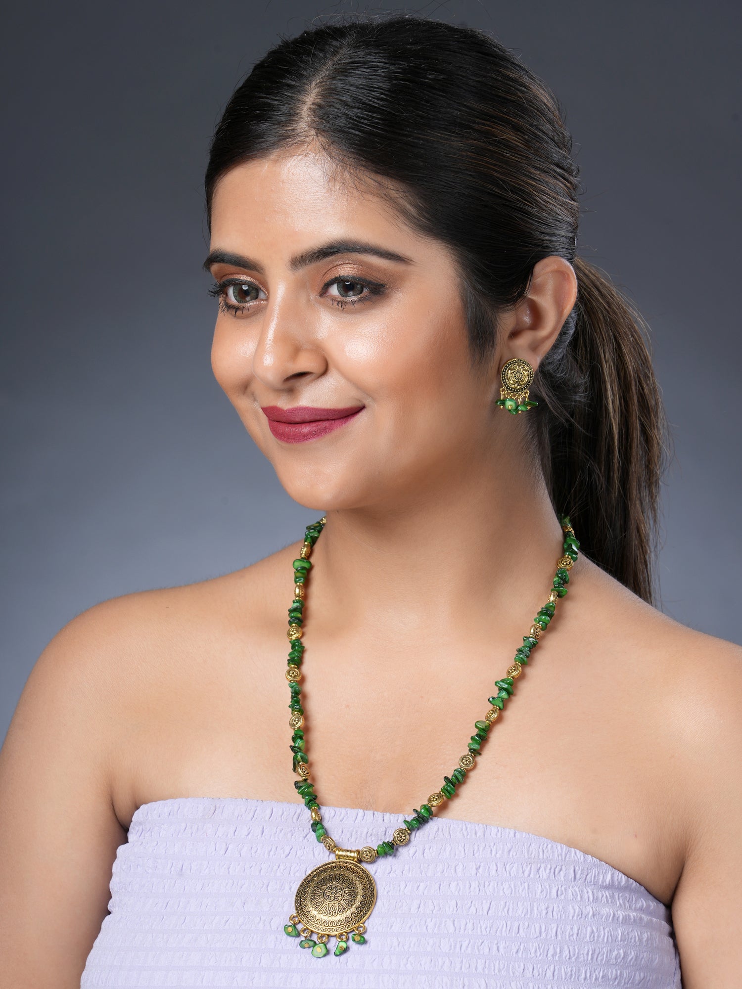 Girl model wearing Eykaa necklace and earrings that features semi precious stone EYKAA GREEN MOTHER OF PEARL WITH GOLDEN CHARMS AND PENDANT BRACELET