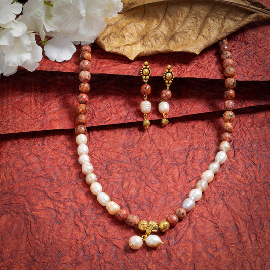 Eykaa Orange Dalmatian And Freshwater Pearl Necklace With Earrings  On A Textured Red Background With White Flowers.