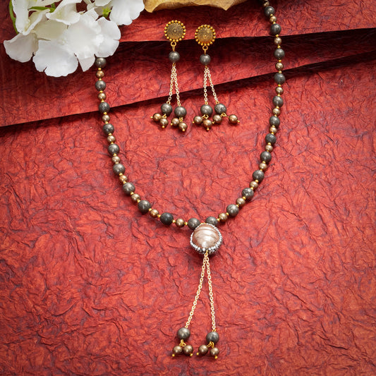 Eykaa Pyrite With Shell Pearls And Shell Pearl Pendant Necklace On A Textured Red Background With White Flowers.