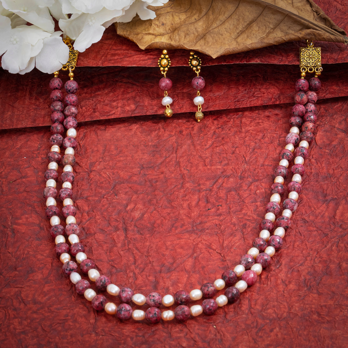 Eykaa Dalmatian And Freshwater Pearl Necklace With Earrings On A Textured Red Background With White Flowers.
Eykaa
stone jewellery
womens jewellery
earing for women
bracelet for women
necklace for women
jewellery stores