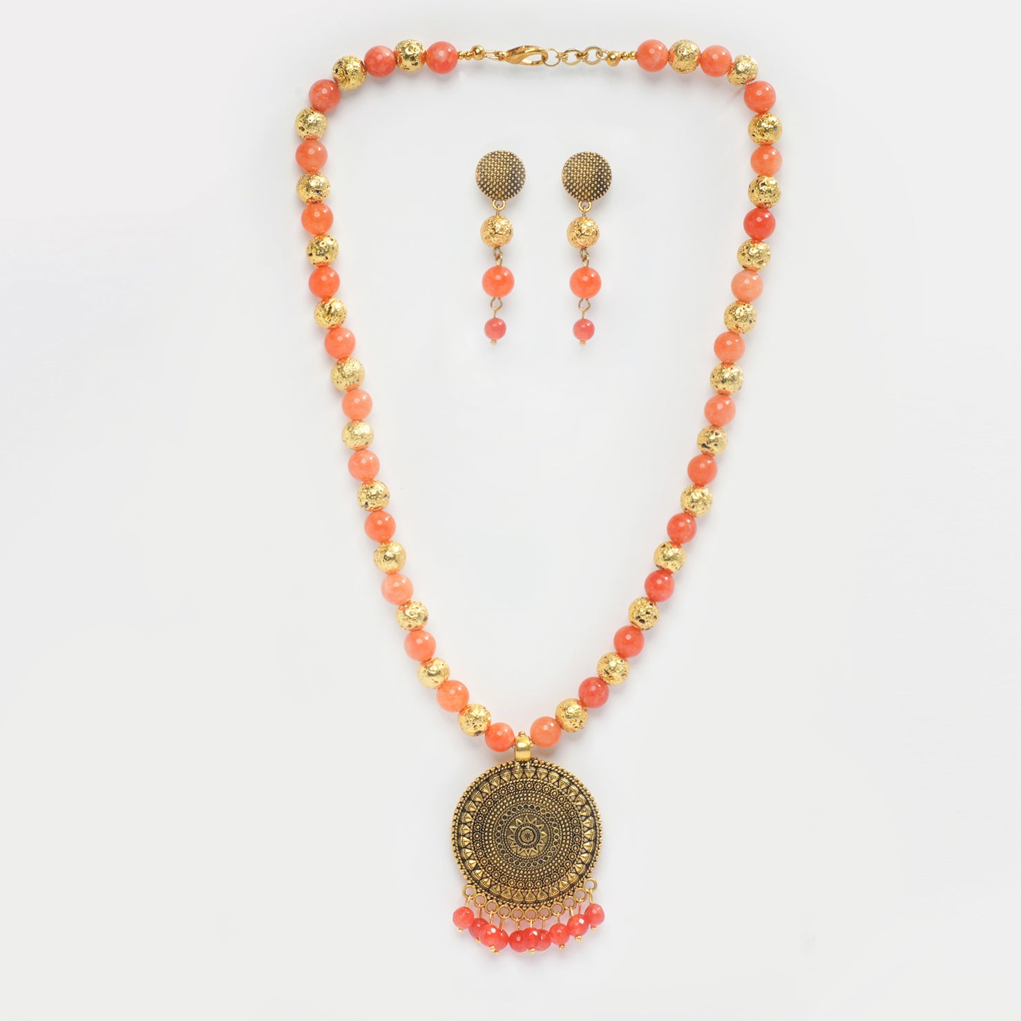 Eykaa necklace and earrings that has orange jade, golden lava semi precious stones and golden pendant with white background