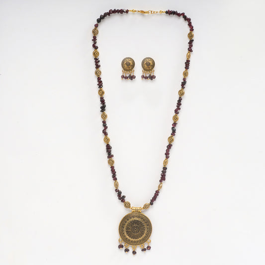 Eykaa necklace and earrings set features garnet semi precious stone with golden charms and pendant on white background.
