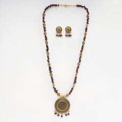 Eykaa necklace and earrings set features garnet semi precious stone with golden charms and pendant on white background.
