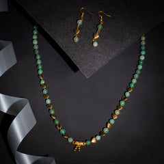 Eykaa green aventurine, golden hematite and shell pearls semi precious stone necklace and earrings on black background.