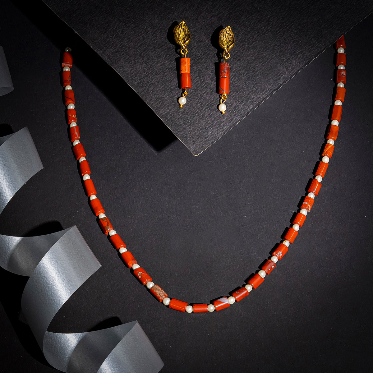 Eykaa brand red jasper with shell pearls semi precious stone earrings and a necklace on black background with silver lace.
