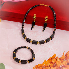 Eykaa brand jewellery set that features semi-precious stone black onyx with hakik beside red  box, pink fabric, and flowers.