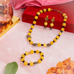 Eykaa yellow jade, pyrite coins and black jade semi precious stone jewelry set beside red box, pink fabric and orange flower