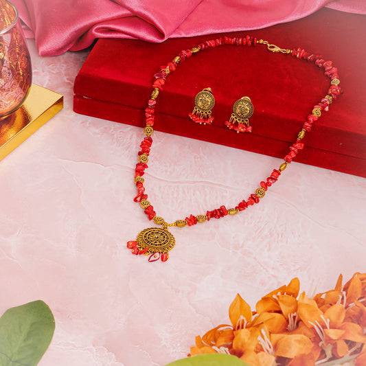 Eykaa brand red mother of pearl semi precious stone necklace, earring and bracelet beside red velvet box, silky pink fabric, and orange flowers