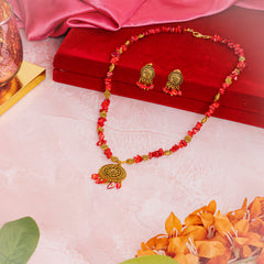 Eykaa brand red mother of pearl semi precious stone necklace, earring and bracelet beside red velvet box, silky pink fabric, and orange flowers