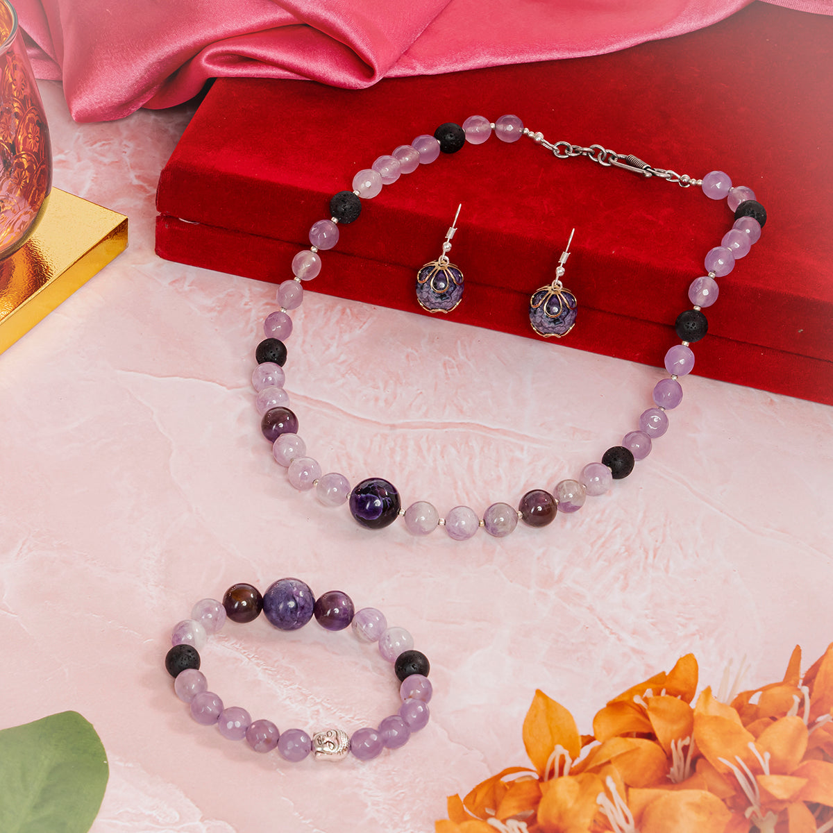 Eykaa jade with kunzite and amethyst semi precious stone jewelry set beside red velvet box, pink fabric, and orange flowers