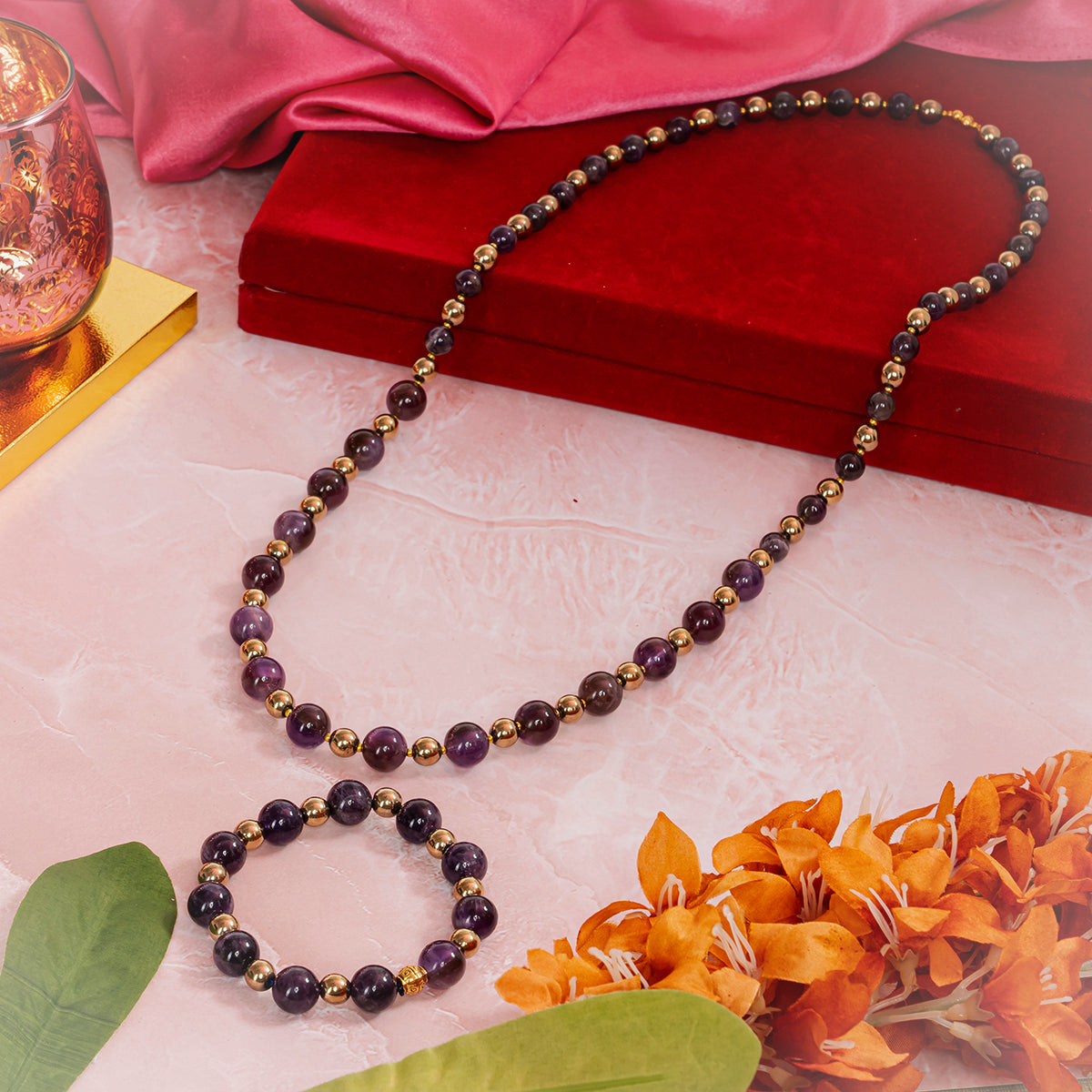 Eykaa black onyx, black tourmaline, and agate semi precious stone necklace and bracelet beside red jewelry box and flower