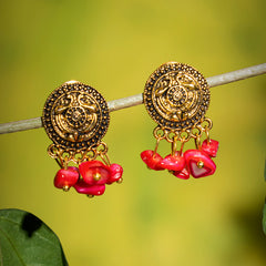 Eykaa earrings that features red mother of pearl semi precious stone hanging on a thin branch with green background 