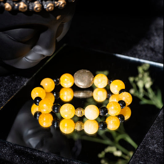 Eykaa YELLOW JADE WITH PYRITE COINS AND FACETED BLACK JADE BRACELET with black background beside silver lace.