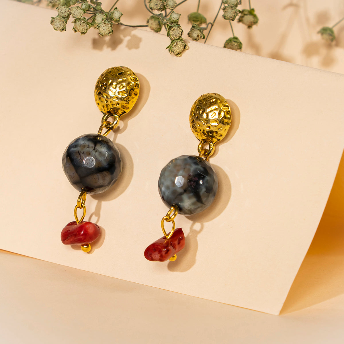 Eykaa Agate With Coral And Golden Diamond Charms Earrings set against a beige background with green baby's breath flowers.