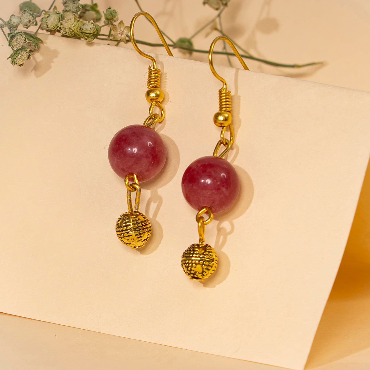 Eykaa pink jade, shell pearls with golden beads and charm semi precious stone earrings hanging on cream colour table card.