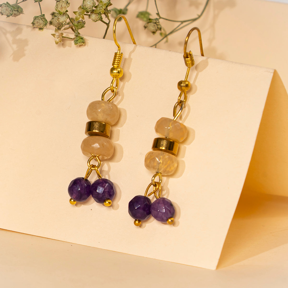 Eykaa yellow calcedonia, jade, and golden hematite semi precious stone earrings on cream background.