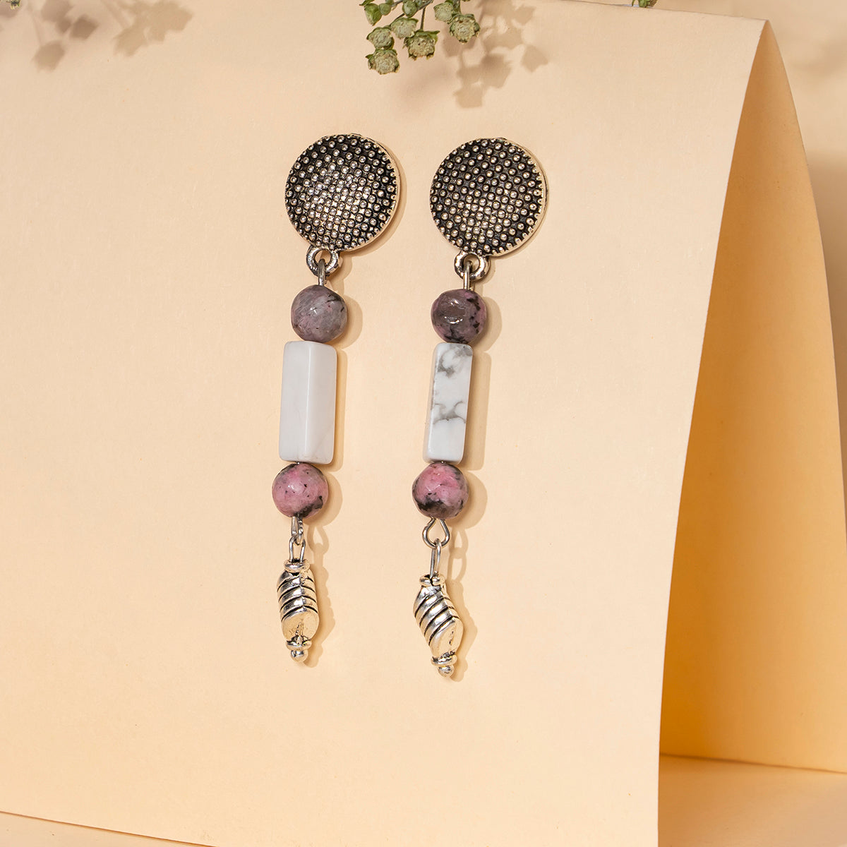 Eykaa white howlite with dalmatian and silver charms semi precious stone earrings on cream background.