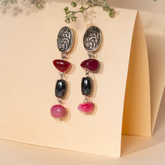 Eykaa earrings that feature pink agate and hematite semi precious stones over cream coloured calender folder and background