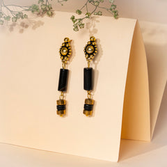 Eykaa Agate Golden Hematite Earrings Set Against A Beige Background With Green Baby's Breath Flowers.