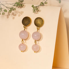 Eykaa  Rose Quartz With Golden Diamond Charms  Earrings Set Against A Beige Background With Green Baby's Breath Flowers.