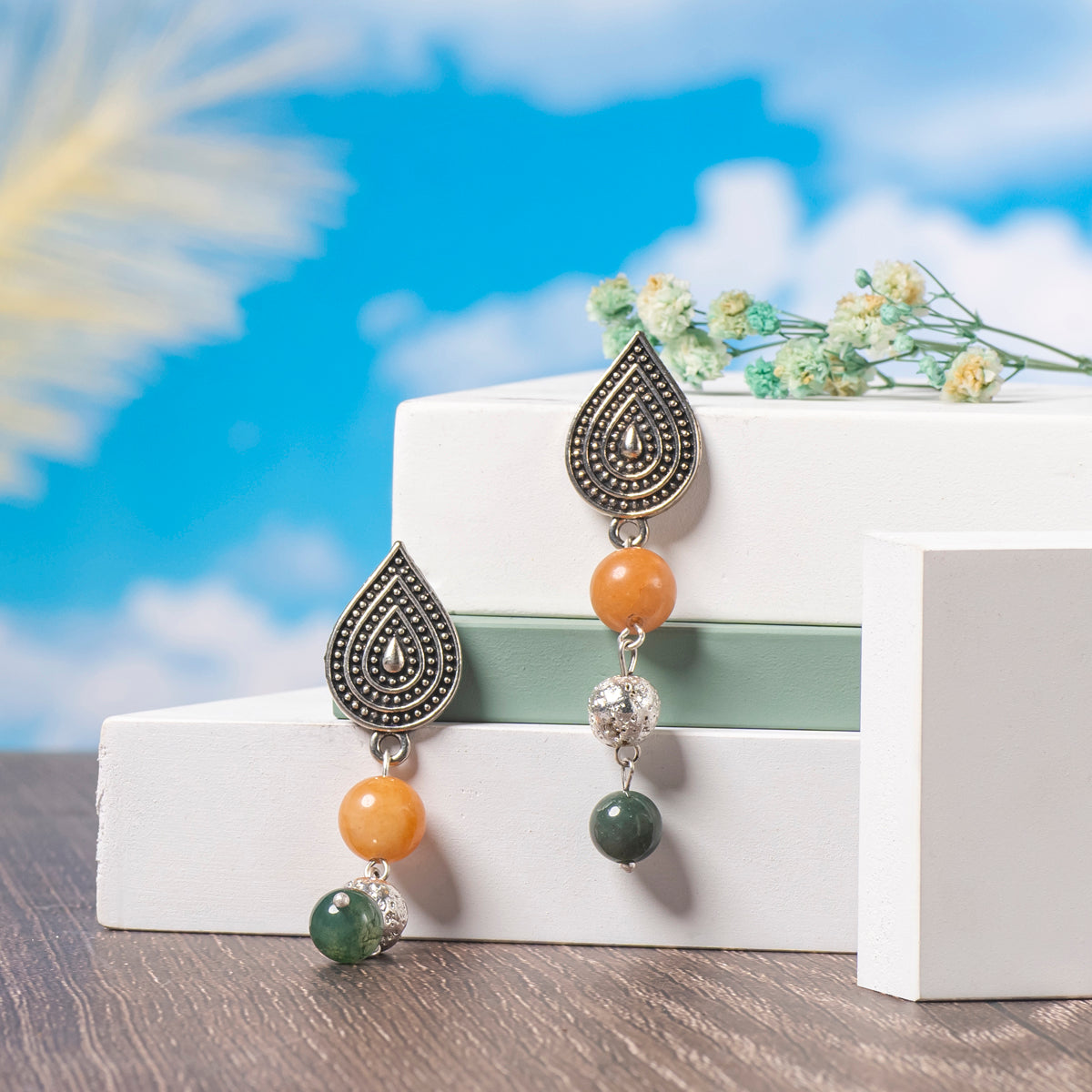 Eykaa Orange Aventurine, Indian Agate Earrings Displayed On A White And Pastel Green Platform With Sky And Clouds Background

Eykaa
stone jewellery
womens jewellery
earing for women
bracelet for women
necklace for women
jewellery stores