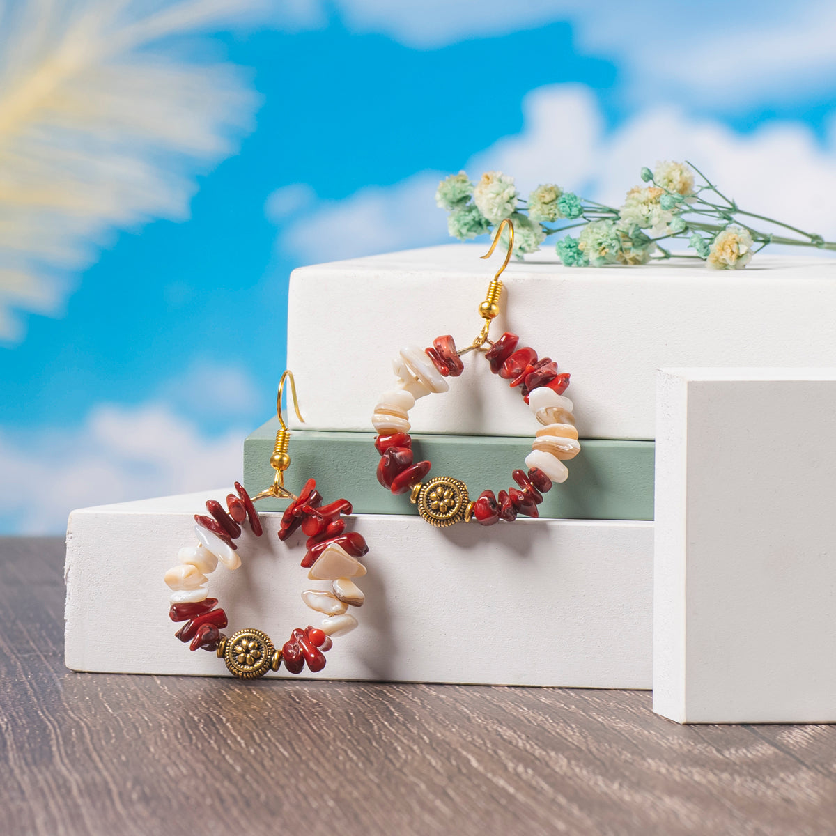  Eykaa White Mother Of Pearl And Coral Earrings Displayed On Multi-tiered Platform With Sky And Clouds Background.