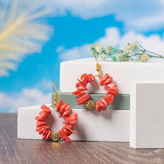 Eykaa Pure Coral Earrings Displayed On Multi-tiered Platform With Sky And Clouds Background.