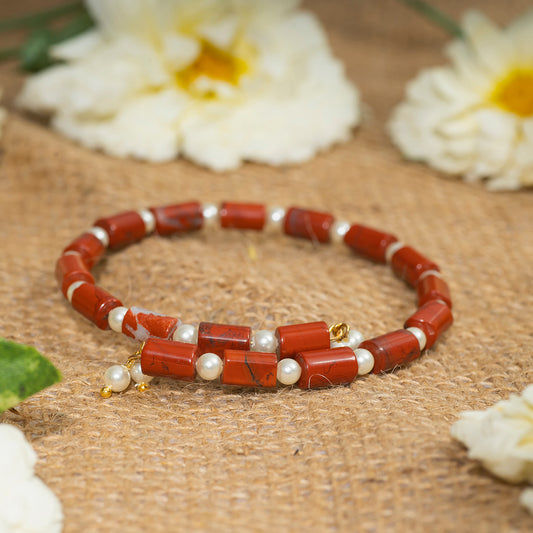 Eykaa brand red jasper with shell pearls semi precious stone bracelet on sack surface with white flowers.