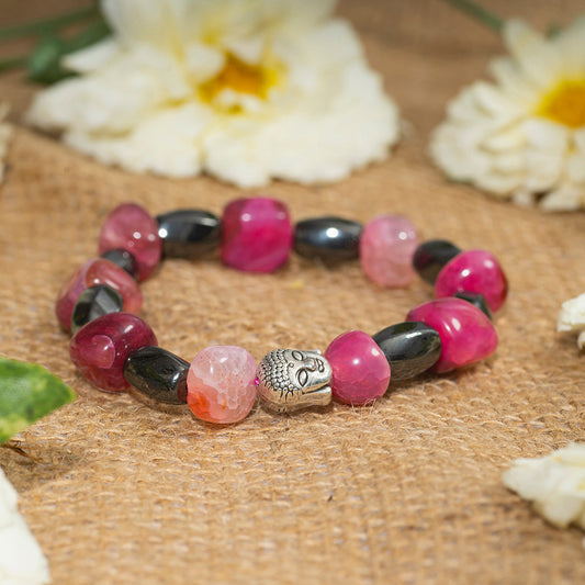 Eykaa brand bracelet that feature pink agate and hematite semi precious stones on sack surface with white flowers.