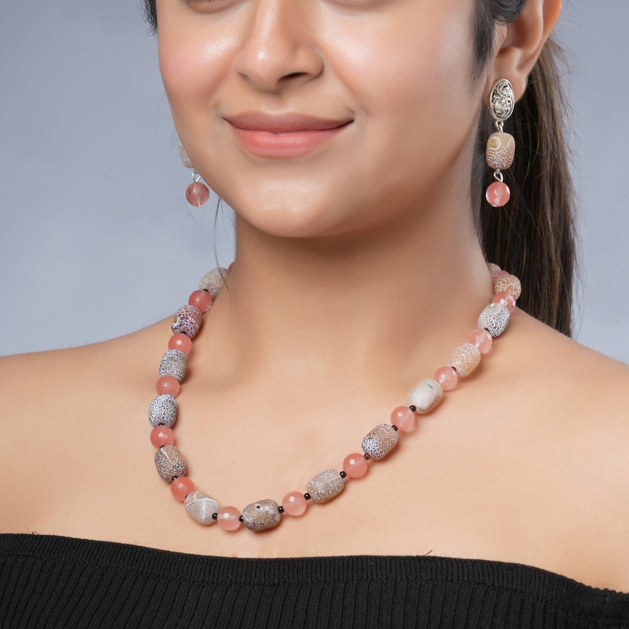 Girl model wearing Eykaa necklace and earrings that feature cherry quartz, agate and black onyx semi precious stones