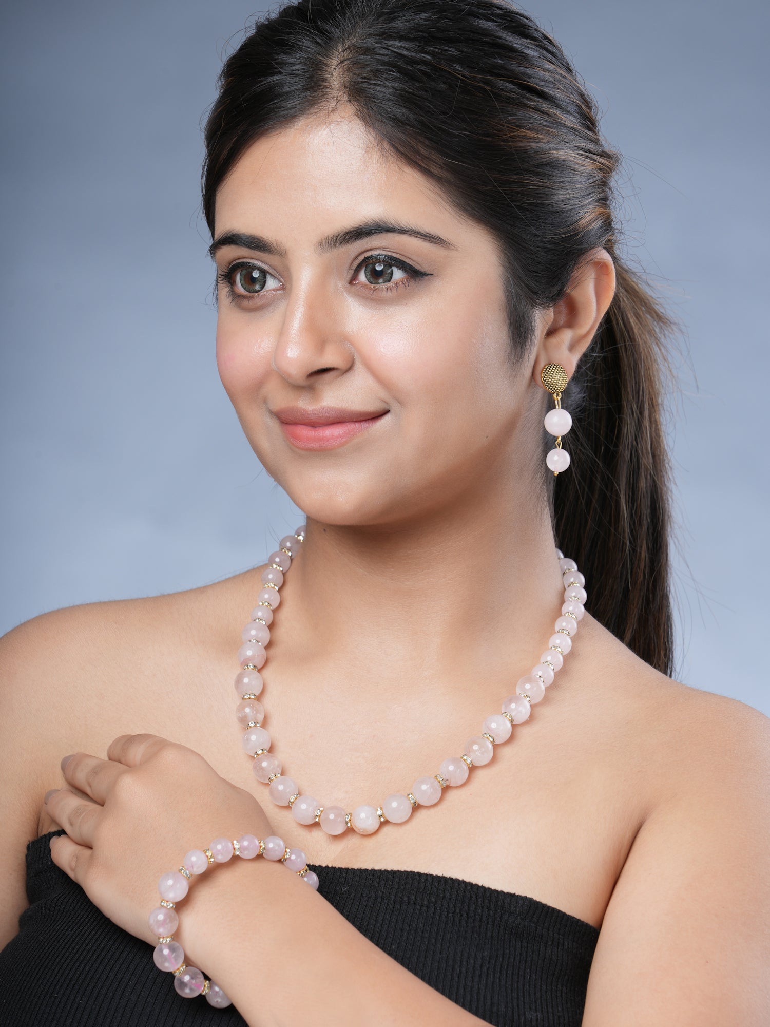 Girl model Wearing Eykaa Rose Quartz With Golden Diamond Charms Necklace With Earrings And A Bracelet.