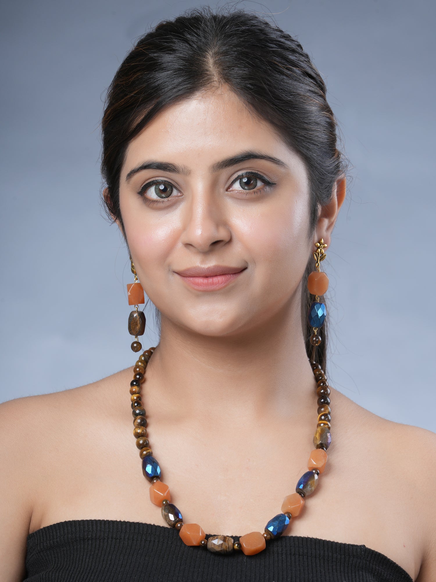 Girl model wearing Eykaa necklace and earrings that have semi precious stone tiger eye, hematite with carnelian.Eykaa TIGER EYE AND HEMATITE WITH CARNELIAN NECKLACE