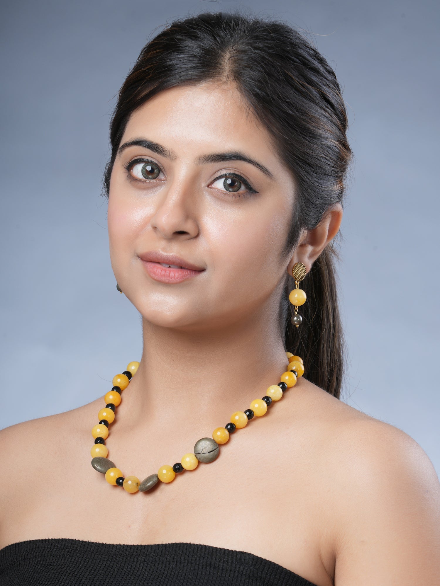 Girl model wearing Eykaa necklace and earrings that features semi precious stone EYKAA YELLOW JADE WITH PYRITE COINS AND FACETED BLACK JADE BRACELET 