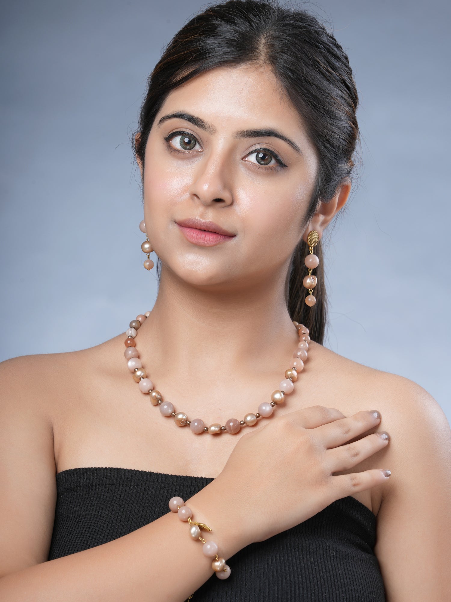 Girl wearing Eykaa peach moonstone, freshwater pearl and shell pearls semi-precious stone necklace, earrings and bracelet