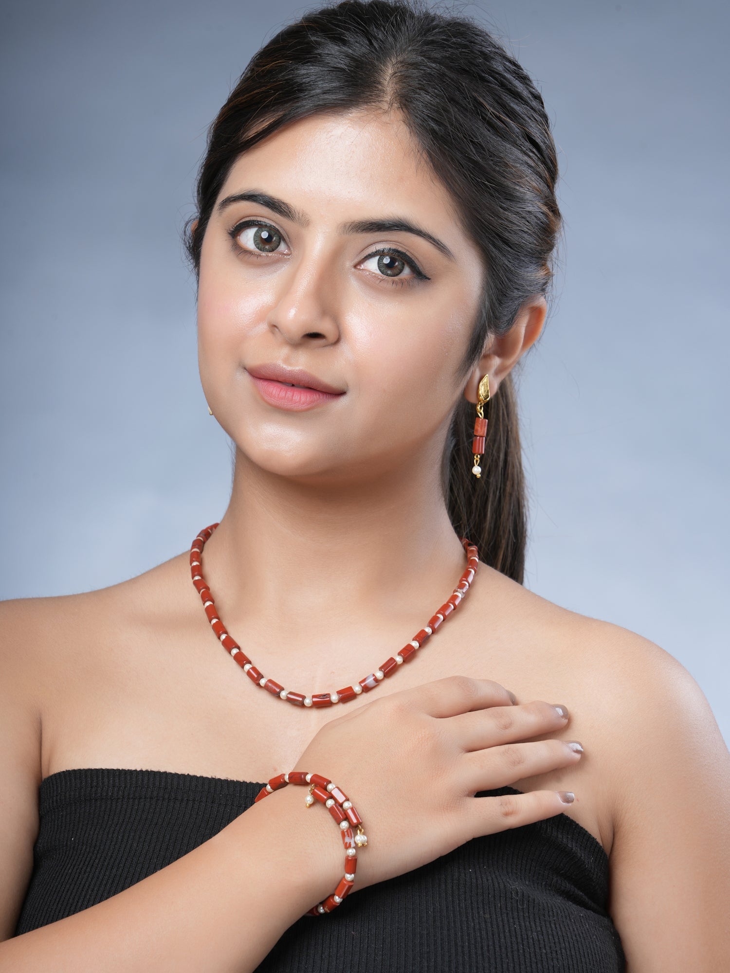 Girl model wearing Eykaa brand red jasper with shell pearls semi precious stone necklace, earrings and bracelet.