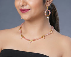Girl model wearing Eykaa cherry quartz with golden charms and shell pearls semi precious stone earrings and necklace.