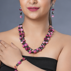 Girl model wearing Eykaa necklace, earrings and bracelet that feature pink agate and hematite semi precious stones.