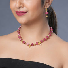 Girl model wearing Eykaa necklace and earrings that features semi precious stone EYKAA PINK JADE WITH SHELL PEARLS AND GOLDEN BEADS WITH GOLDEN CHARMS BRACELET