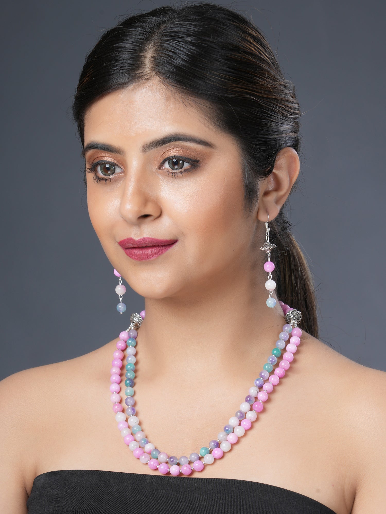 Girl model wearing Eykaa layered necklace and earrings that feature pink and multicoloured semi precious stone jade. 