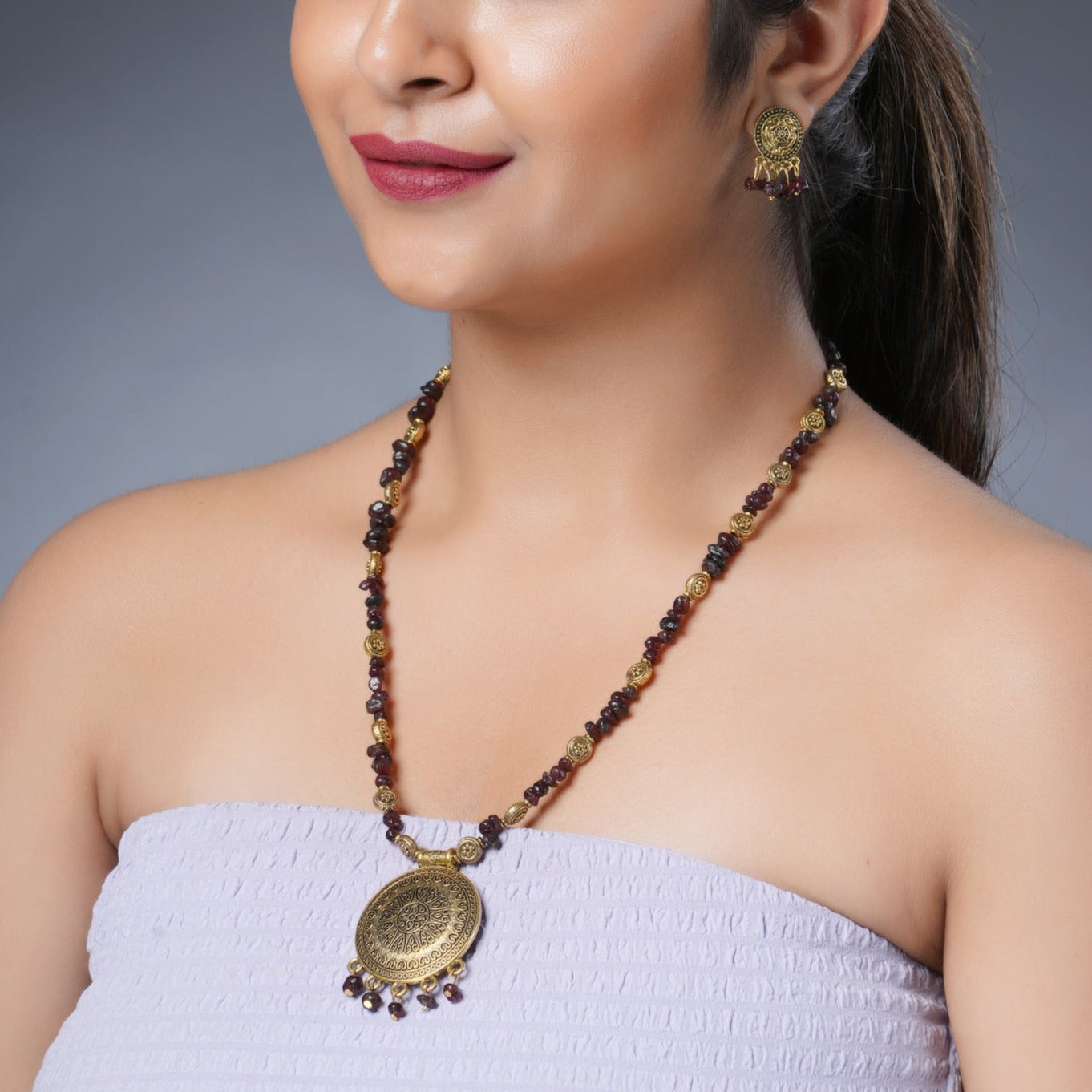 Girl model wearing Eykaa necklace and earrings that features semi precious stone  EYKAA GARNET WITH GOLDEN CHARMS AND GOLDEN PENDANT 