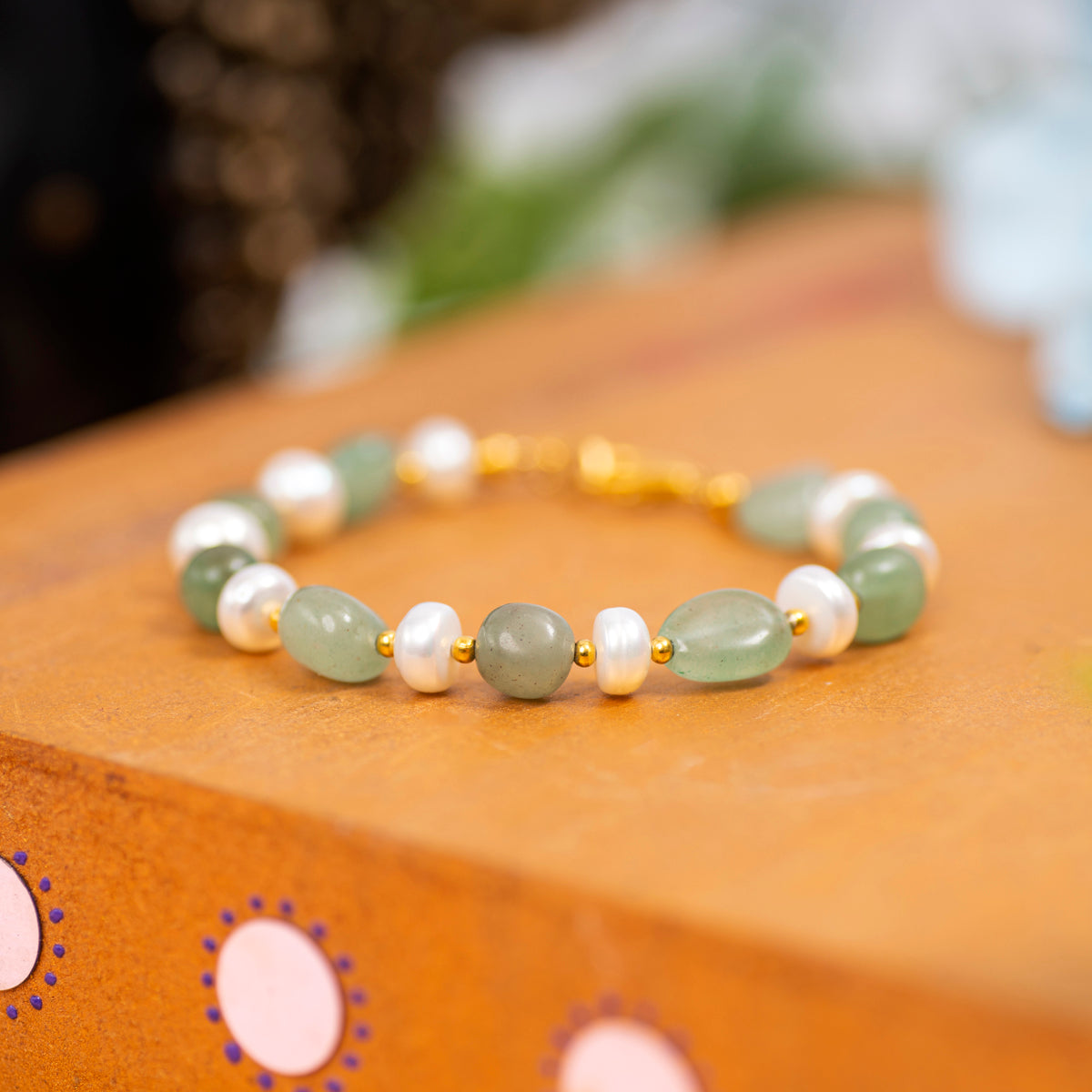 Eykaa Green Aventurine With Freshwater Pearl, Silver Strawberry Quartz, And Shell Pearl Bracelet Displayed On A Textured Orange Surface.