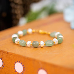 Eykaa Green Aventurine With Freshwater Pearl, Silver Strawberry Quartz, And Shell Pearl Bracelet Displayed On A Textured Orange Surface.